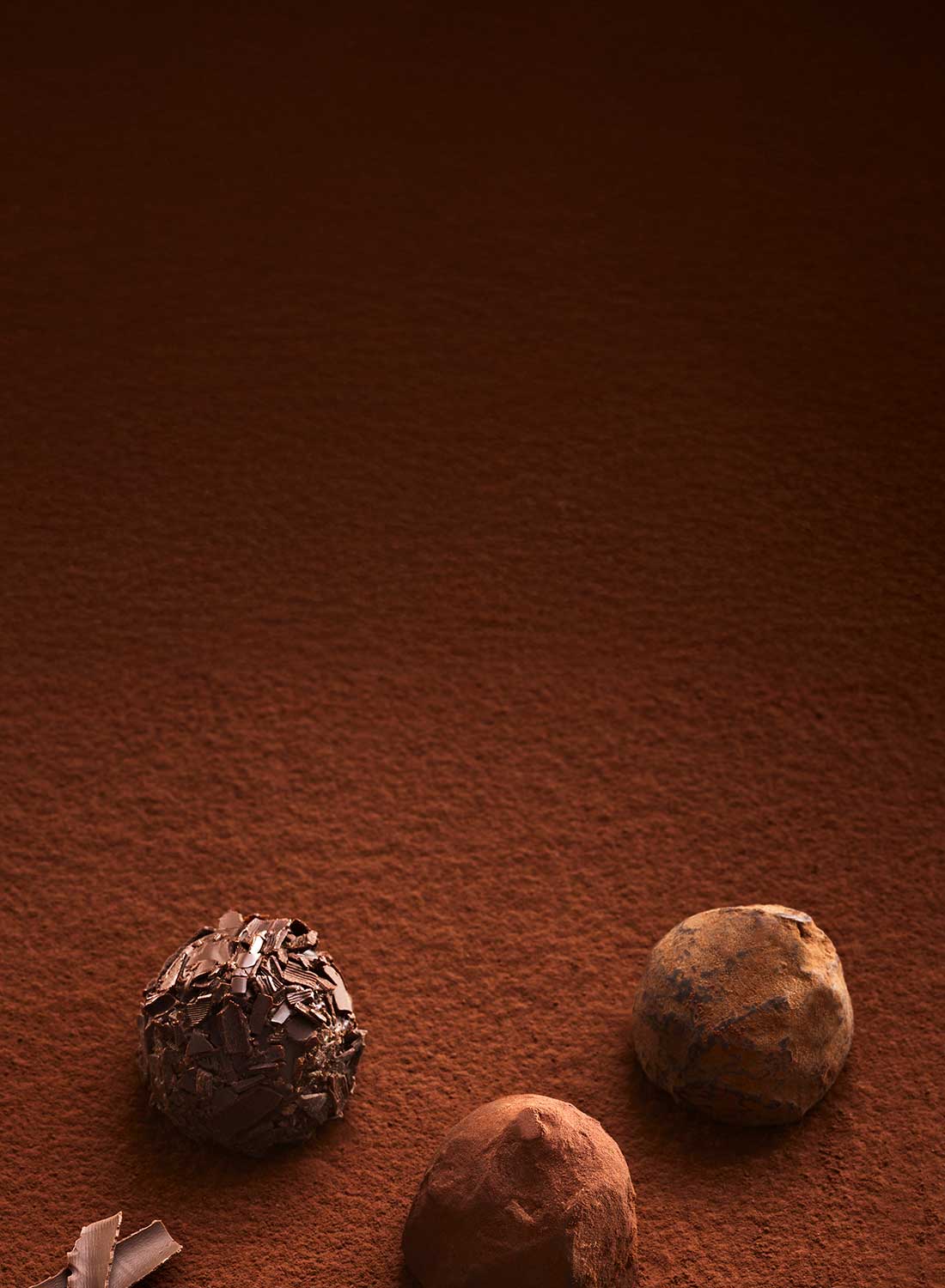 Three Godiva chocolate truffles on a brown surface